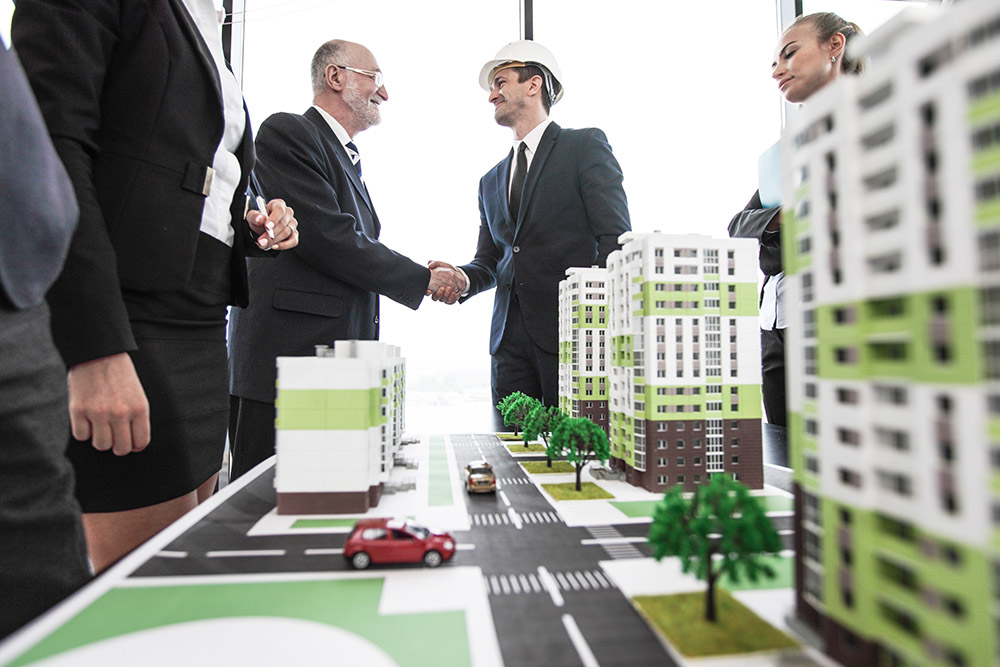 People shake hands over models of new developments